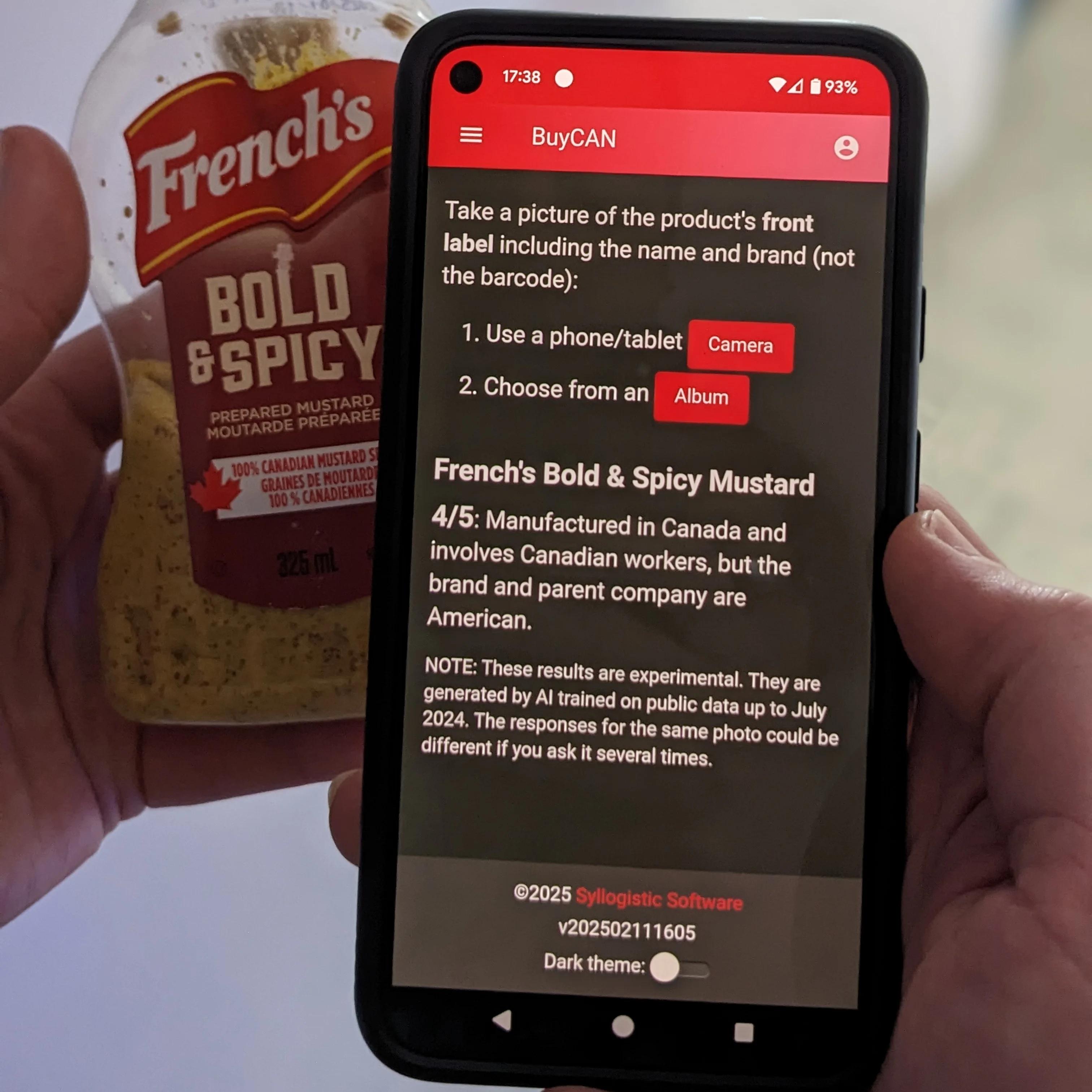 A phone running BuyCAN next to a mustard bottle, showing the product it identified from a photo of the label and a rating explaining where the product and company are from